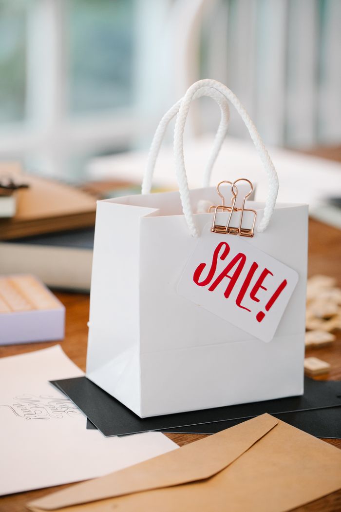 Stylish white paper bag with a sale tag on a wooden table, perfect for promotions.